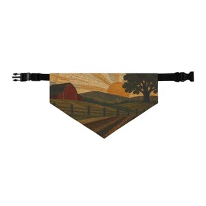 Può includere: Una bandana triangolare per animali domestici con una scena paesaggistica tessuta che mostra un fienile rosso, colline verdi, un grande albero e un sole dorato nel cielo. Il tessuto è fissato a un cinturino in nylon nero regolabile con fibbia.