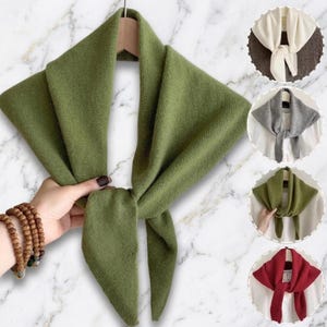 May include: A triangular knit scarf in olive green, featuring a soft, textured fabric. The scarf is tied in a simple knot at the centre. Additional circular insets display the same scarf style in white, grey, olive green, and deep red colours.