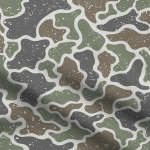 May include: A fabric pattern featuring an irregular camouflage design with organic, rounded shapes in shades of olive green, dark charcoal gray, and muted brown, all set against a light gray background with a distressed, speckled texture.