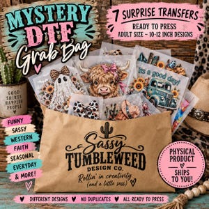 May include: A brown paper bag labeled Sassy Tumbleweed Design Co. containing seven mystery DTF transfers. The visible designs include a ghost with a leopard print bow, a highland cow with a pink bow, and a blue truck with the text Its a good day.