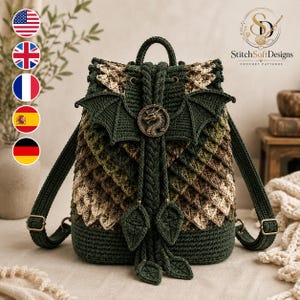 May include: A dark green crochet backpack featuring a dragon wing design, layered scale-like textures in shades of green and beige, a central circular bronze-toned dragon medallion, and two braided drawstring cords with leaf-shaped ends.