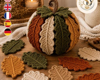 May include: A crocheted pumpkin featuring alternating vertical segments in shades of burnt orange, cream, and olive green, topped with a brown stem and green leaves. Several individual crocheted leaves in matching colours are arranged around it.