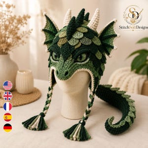 Peut inclure: Un bonnet en crochet sur le thème du dragon, de couleur verte, avec des écailles texturées, des oreilles pointues et des cornes crème. Il comporte deux longues oreillettes tressées avec des pompons et une longue queue de dragon articulée.