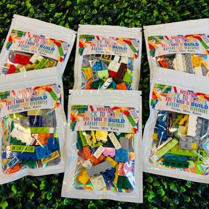 May include: Six clear plastic bags with colorful Lego bricks inside. Each bag has a label that says "Welcome Back to School Can't Wait to Build A Great Year Together! From: Mrs. Kara"