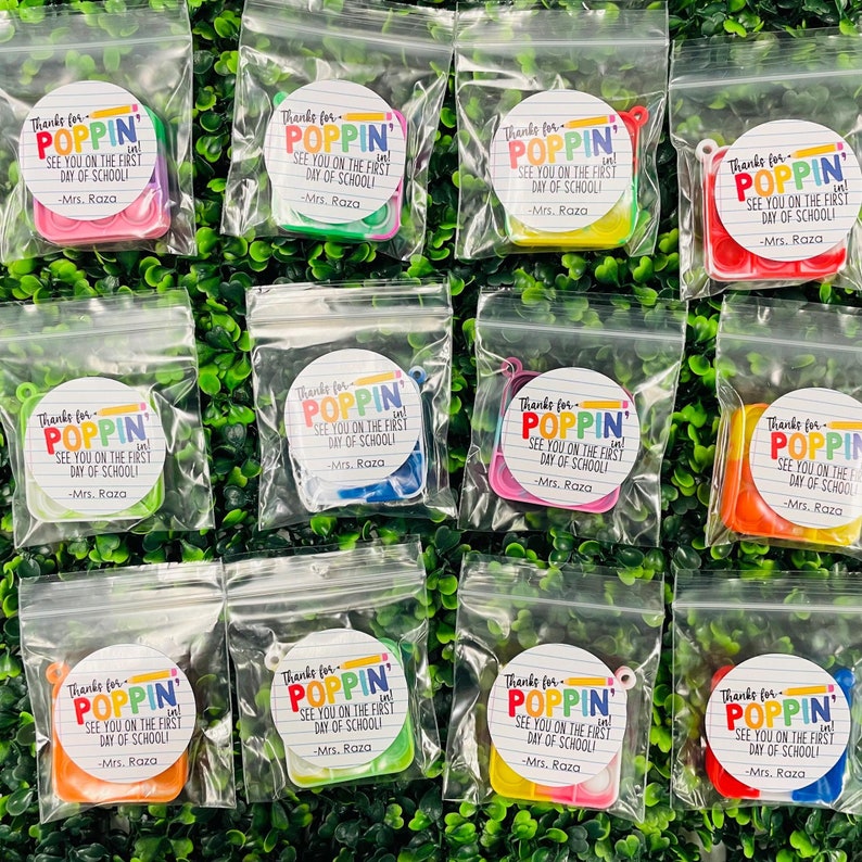 Puede incluir: Doce peque&ntilde;as bolsas de pl&aacute;stico transparentes que contienen cada una un juguete pop-it de colores y una pegatina redonda que dice "Gracias por Poppin' &iexcl;Nos vemos el primer d&iacute;a de escuela! -Sra. Raza"