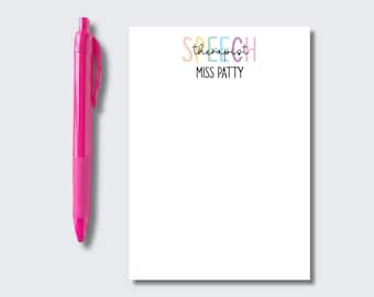 Puede incluir: Un bolígrafo retráctil de color rosa brillante colocado junto a un bloc de notas rectangular blanco. El bloc de notas presenta la palabra SPEECH en letras de colores pastel, la palabra therapist en cursiva negra y el nombre MISS PATTY en texto negro.