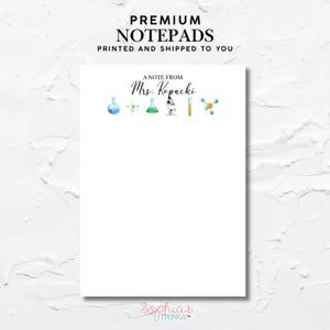 May include: A white notepad with the text "PREMIUM NOTEPADS" and "PRINTED AND SHIPPED TO YOU" at the top. The notepad features watercolor illustrations of science lab equipment and the text "A NOTE FROM Mrs. Kopacki".