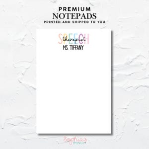 Op de afbeelding: Een witte notitieblok met bovenaan de tekst "PREMIUM NOTEPADS". Daaronder staat "SPEECH therapist" in pastelkleuren, gevolgd door "MS. TIFFANY" in zwart. De onderkant van het notitieblok heeft de tekst "Sophia's THINGS".