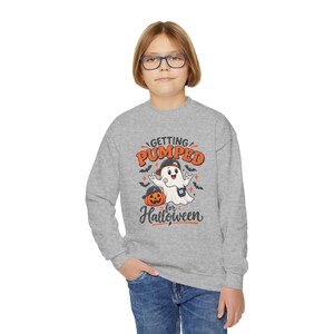 May include: A heather gray long-sleeve sweatshirt featuring a graphic of a white ghost wearing a baseball cap and a blue insulin pump, standing next to a jack-o'-lantern. The text reads "GETTING PUMPED for Halloween" in orange and black.