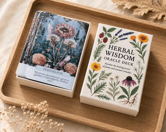 May include: A deck of Herbal Wisdom oracle cards in a white box with botanical illustrations of flowers and berries. The box features the text Herbal Wisdom Oracle Deck. Beside it, an open card shows a dandelion illustration and the text Nurture abundance; grow a garden of prosperity within you.