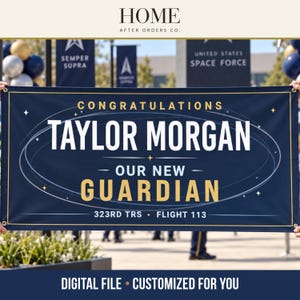 May include: A rectangular navy blue banner featuring gold and white text that reads CONGRATULATIONS TAYLOR MORGAN OUR NEW GUARDIAN 323RD TRS FLIGHT 113. The design includes a thin white orbital ring graphic and small star accents on a dark background.