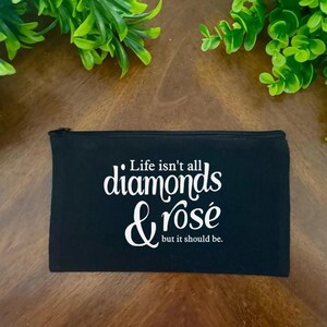 May include: Black zippered pouch with the text "Life isn't all diamonds & rosé but it should be."