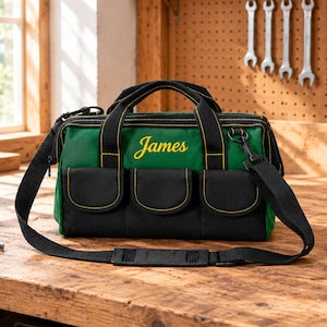 Puede incluir: Una bolsa de herramientas verde y negra con el nombre James bordado en letra cursiva amarilla en la parte frontal. La bolsa incluye tres bolsillos delanteros, asas negras y una correa de hombro negra extraíble con costuras amarillas.