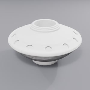 Op de afbeelding: Een wit, schotelvormig object met een centrale ronde opening en een reeks kleine, gelijkmatig verdeelde inkepingen langs de bovenrand. Het onderste gedeelte heeft een donker, gefacetteerd, geometrisch oppervlak dat taps toeloopt.