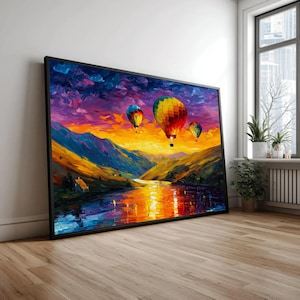 Könnte beinhalten: Ein rechteckiger gerahmter Kunstdruck mit einem Ölgemälde von drei Heißluftballons, die bei Sonnenuntergang über einem Fluss und Bergen schweben. Der Himmel ist eine lebendige Mischung aus Violett, Orange und Gelb mit Spiegelungen.