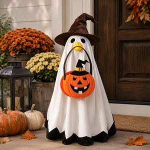 May include: A white ghost decoration wearing a brown witch hat and holding an orange jack-o'-lantern candy bucket. The ghost has a yellow beak, black eyes, and a black hem at the bottom. The pumpkin bucket features a black witch hat and face.