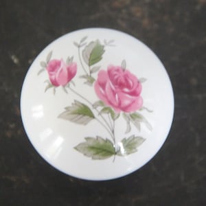 May include: White ceramic lid with a floral design featuring pink roses and green leaves.
