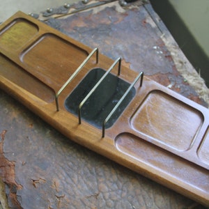 May include: A wooden tray with multiple compartments and a small mirror with a brass divider. The tray is made of dark wood and has a smooth finish.