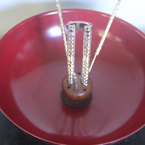 May include: A red bowl with a silver nutcracker in the center. The nutcracker has three prongs and a wooden base.