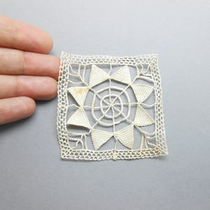 Peut inclure: Napperon carré en dentelle blanc cassé avec un motif géométrique. Le centre présente un motif circulaire, entouré de formes triangulaires. Les bords sont finis avec une bordure délicate et festonnée. Le napperon mesure environ 7,6 cm de côté.