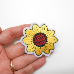 Peut inclure: Écusson de tournesol brodé avec des pétales jaunes, un centre rouge et une bordure blanche. Le patch est un motif floral, adapté aux vêtements ou aux accessoires.
