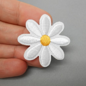 Puede incluir: Parche de margarita blanca bordada con un centro amarillo. El parche tiene un diámetro de aproximadamente 5 cm.