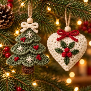 K&ouml;nnte beinhalten: Zwei geh&auml;kelte Anh&auml;nger an Jutekordeln. Einer ist ein gr&uuml;ner, dreistufiger Weihnachtsbaum mit braunem Stamm, wei&szlig;en gestickten Sternen und roten Beeren. Der andere ist ein cremefarbenes Herz mit roter Schleife, gr&uuml;nen Bl&auml;ttern und roten Beeren.