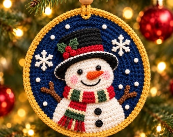May include: A round, crocheted Christmas ornament featuring a white snowman with a black top hat, orange carrot nose, and a red and green striped scarf. The snowman is set against a dark blue background with white snowflakes.