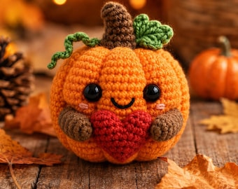 May include: A crocheted orange pumpkin with a brown stem, a green leaf, and a green vine. The pumpkin has black plastic eyes, a stitched smile, pink cheeks, and holds a red crocheted heart in its brown arms, all crafted from yarn.