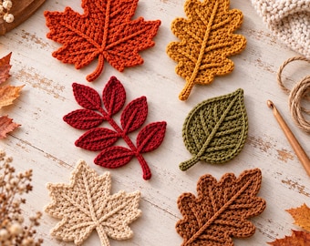 May include: A collection of six crocheted leaf appliques in various shapes and colors, including orange, yellow, red, olive green, cream, and brown. The leaves feature detailed stitched veins and are arranged on a white wooden surface.