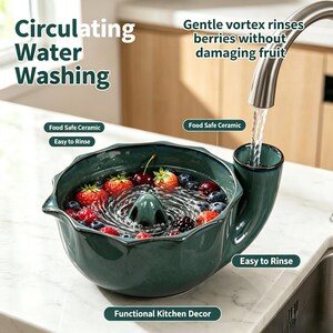 Puede incluir: Un cuenco de cerámica verde oscuro para lavar bayas con un sistema de vórtice central y una entrada de agua lateral. El cuenco contiene fresas, arándanos y moras frescas. El texto dice: Circulating Water Washing, Gentle vortex rinses berries without damaging fruit, Food Safe Ceramic, Easy to Rinse, Functional Kitchen Decor.