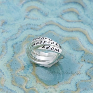 May include: Silver ring with three bands, each engraved with a name: Henry, Mackenzie, and Adam.