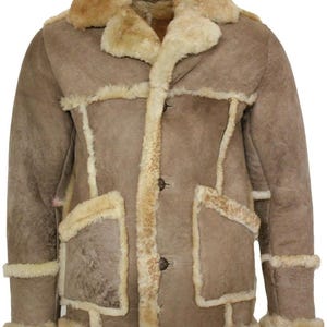 May include: A tan suede jacket featuring a thick cream-colored shearling lining, a wide notched collar, and three dark brown buttons down the front. The garment includes two large patch pockets and shearling trim along the cuffs and hem.