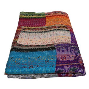 K&ouml;nnte beinhalten: Eine rechteckige Patchwork-Decke mit verschiedenen bunten Stoffbahnen in Blau-, Lila-, Orange-, Rot- und Wei&szlig;t&ouml;nen. Das Textil ist mit sichtbaren horizontalen Steppn&auml;hten in kontrastierenden Farben &uuml;ber die gesamte Oberfl&auml;che versehen.