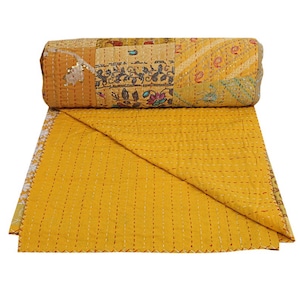 May include: A mustard yellow cotton quilt featuring intricate kantha stitching and a patchwork design on the rolled top section. The fabric displays various floral and paisley patterns in muted tones, with a solid yellow underside visible.