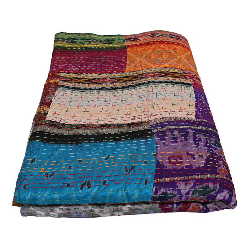 K&ouml;nnte beinhalten: Eine rechteckige Patchwork-Decke mit verschiedenen bunten Stoffbahnen in Blau-, Lila-, Orange-, Rot- und Wei&szlig;t&ouml;nen. Das Textil ist mit sichtbaren horizontalen Steppn&auml;hten in kontrastierenden Farben &uuml;ber die gesamte Oberfl&auml;che versehen.