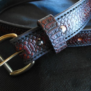 Peut inclure: Une ceinture en cuir marron avec un motif gaufré de crocodile et une boucle en laiton.