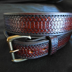 May include: A brown leather belt with a snakeskin embossed design and a brass buckle.