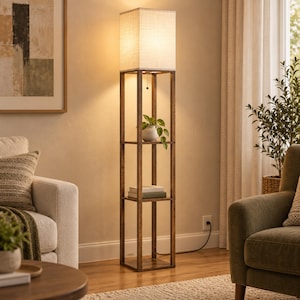 May include: A tall, rectangular floor lamp with a dark brown wooden frame featuring three open shelves. The top shelf holds a small potted green plant, the middle shelf contains two stacked books, and the top features a square fabric lampshade.