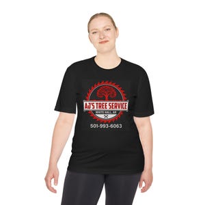 May include: A black short-sleeve t-shirt featuring a red circular saw blade graphic with a tree silhouette in the center. The text reads AJ'S TREE SERVICE, WHITE HALL, AR, and the phone number 501-993-6063, with a small crossed axe icon below.