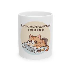 May include: A white ceramic mug featuring a cartoon illustration of an orange tabby cat sitting at a desk with a laptop, a cup of coffee, and a piece of toast. The text above the cat reads, "ME OPENING MY LAPTOP JUST TO STARE AT IT FOR 20 MINUTES."