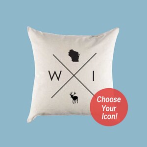 Puede incluir: Una almohada blanca con un dise&ntilde;o en blanco y negro que presenta el estado de Wisconsin, las letras "WI" y la silueta de un ciervo. El texto "&iexcl;Elige tu icono!" est&aacute; en un c&iacute;rculo rojo.
