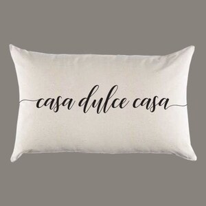 May include: Cream-colored rectangular pillow with the phrase "casa dulce casa" in elegant black script. The pillow has a soft, inviting appearance, perfect for home decor. The text is centered, creating a balanced and stylish design.