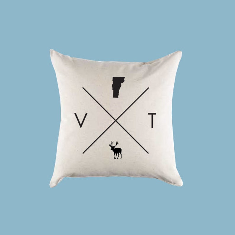 May include: A white pillow with a black silhouette of the state of Vermont, a deer, and the letters "VT" crossed over each other.