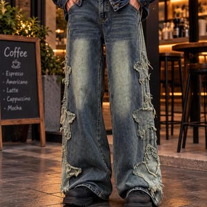 May include: Wide-leg blue denim jeans featuring distressed star-shaped patches along the outer seams with frayed edges. The jeans have a faded wash, a classic button fly, and are paired with a dark blue denim jacket and black shoes.