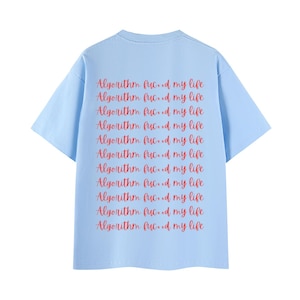 May include: A light blue short-sleeved t-shirt featuring the red text "Algorithm fucxd my life" printed repeatedly in eleven horizontal rows across the back. The garment has a crew neckline and a standard fit with short sleeves and a straight hem.