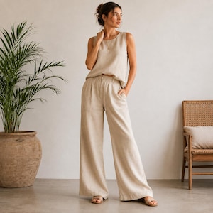 Puede incluir: Un top sin mangas de lino en color beige y pantalones anchos a juego. El top presenta un cuello redondo y un corte relajado, mientras que los pantalones tienen un diseño de cintura alta con una silueta holgada y fluida hasta los tobillos.