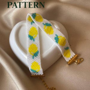 Puede incluir: Una pulsera de cuentas con fondo blanco y un patrón repetitivo de limones amarillos y hojas verde azulado. La pulsera incluye terminales de metal dorado, un cierre de mosquetón y una cadena ajustable. El texto PDF PATTERN es visible.