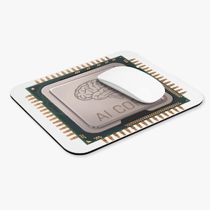 May include: A rectangular mouse pad featuring a graphic of a computer processor chip with a brain illustration and the text AI CORE printed on it. A smooth white computer mouse rests on the surface of the pad, partially covering the printed text.
