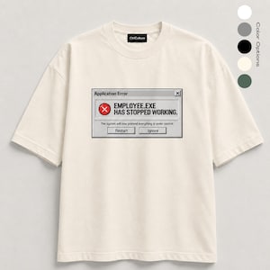 Può includere: Una t-shirt a maniche corte color bianco sporco con la grafica di una finestra di errore del computer che recita: Application Error, EMPLOYEE.EXE HAS STOPPED WORKING. The system will now pretend everything is under control. Pulsanti Restart e Ignore.